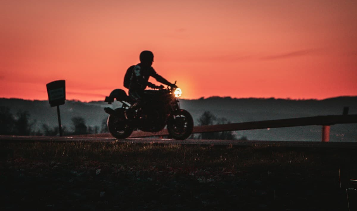 Motorcycle rider silhouetted against a sunset